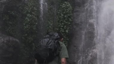 Sırt çantalı erkek turist, ormanda başarı, başarı ve hedefi kutlamak için kollarını kaldırıyor..