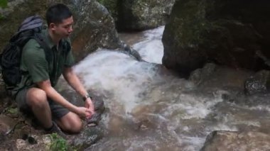 Dağdaki dereden gelen suyla yüzünü yıkayan mutlu bir yürüyüşçü..