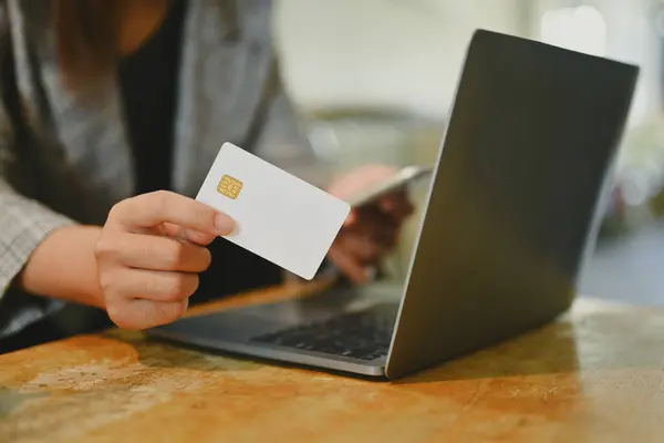 Young woman holding credit card using laptop doing online banking transaction or shopping in online store.