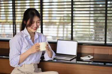 Pozitif Asyalı iş kadını işe ara verip işyerinde kahve içiyor..