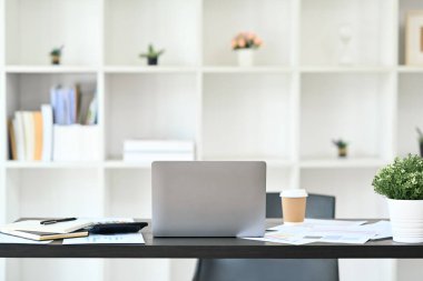 Laptop, belgeler ve ofis malzemeleriyle siyah ahşap masa üzerinde rahat bir iş yeri..