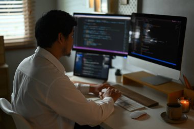 Karanlık odada bilgisayar ekranında şifreli verilerle çalışan yetenekli bir erkek programcı..
