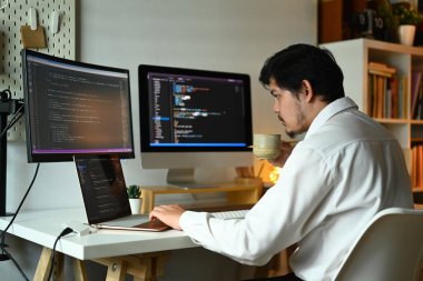 Bilgisayar ekranında şifreli verilerle çalışan konsantre erkek ağ geliştirici. Programlama ve kodlama teknolojileri.
