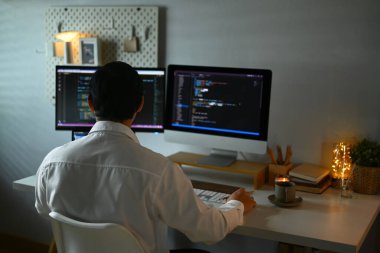 Karanlık odadaki bilgisayar ekranında şifreli verilerle çalışan odaklanmış erkek programcı.