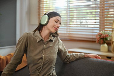 Milenyum kadını kulaklıkla en sevdiği müziği dinliyor ve evdeki kanepede dinleniyor..