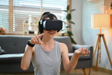 Evde sabah antrenmanı sırasında VR kulaklığı takan gülümseyen sporcu kadın..