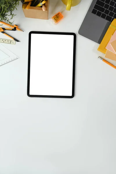 Digital tablet with empty screen, laptop and stationery on white table. Flat lay, top view.
