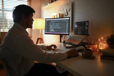 Genç programcı akşam evde bilgisayarda kodlama yapıyor..