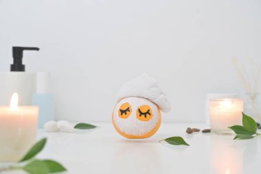 Kozmetik plastik şişeli beyaz arka planda yüz maskeli turuncu meyve. Spa tedavisi kavramı.