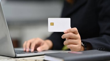 Kredi kartı tutan ve online bankacılık işlemleri için dizüstü bilgisayar kullanan kadınlara odaklan.