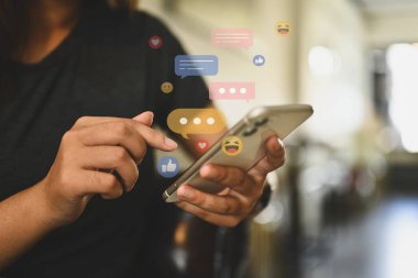 Mesaj, yorum ve benzeri mesaj simgeleriyle cep telefonu kullanan bir kadın. Sosyal medya ve teknoloji kavramı.