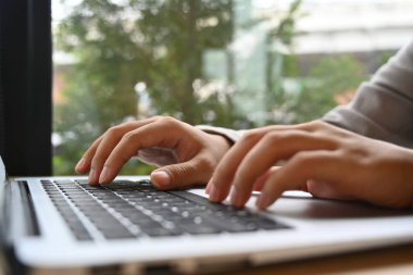 Kapalı kadın işçi elleri dizüstü bilgisayarda yazarken e-postaya cevap verirken ya da bilgi ararken.