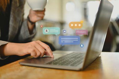 Laptop bilgisayarında yorum yapan, paylaşımda bulunan ve makaleler okuyan kadınların yan görünümü.