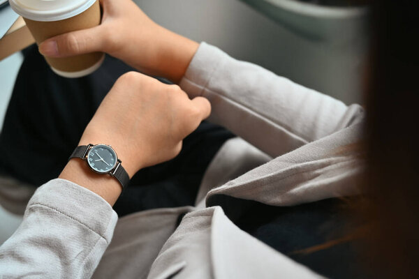 Cropped shot of young businesswoman in formal suit checking time on wrist watch for appointment.