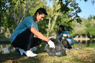 Kamu parkında çöpleri toplayan gönüllü bir erkek. İşbirliği, yardım ve geri dönüşüm kavramı.