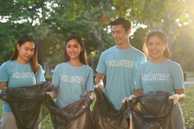 Çöp torbalarıyla birlikte ormanı temizleyen genç gönüllülerden oluşan bir ekip..
