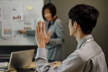 Asyalı erkek işçilerin bir seminerde soru sorarken yan görünümü.
