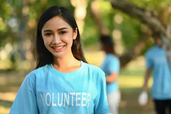 Portrait female volunteer in blue uniform smiling at camera while standing outdoor. Charity and community service concept.