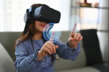 VR kulaklık takan ve sanal düğmeye basan küçük kız dijital arayüzle etkileşimde.