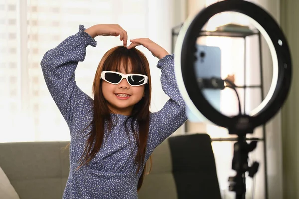 Joyful Asian girl creating her trendy content recording video with smartphone to share on social media