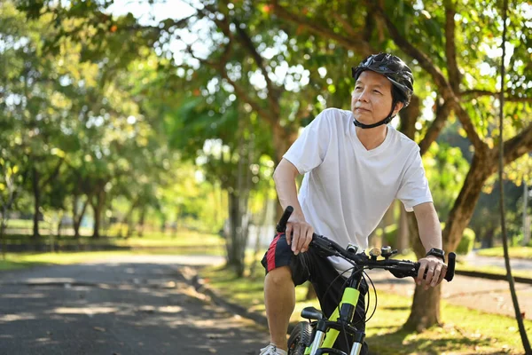 Kasklı Emekli Adam Güneşli Yaz Gününde Parkta Bisiklet Sürüyor — Stok fotoğraf