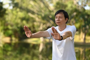 Parkta Qigong egzersizleri yapan konsantre Asyalı son sınıf öğrencisi. Sağlıklı yaşam tarzı kavramı.