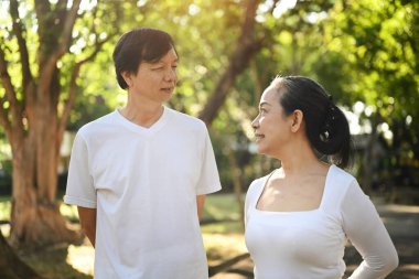 Yaz parkında günlük giysiler içinde birlikte yürüyen güzel bir çift. Emeklilik yaşam tarzı kavramı.