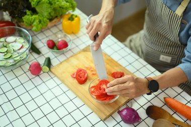 Sağlıklı orta yaşlı bir adamın salata için domates kesmesi. Aktif yaşlılar ve sağlıklı beslenme konsepti