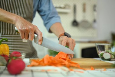 Salata için tahta tahtada sebze doğrayan orta yaşlı bir adam. Sağlıklı yeme kavramı