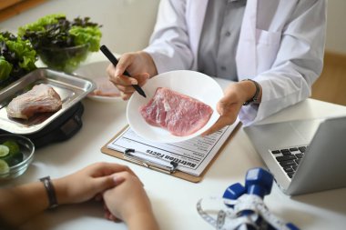 Klinikteki hastaya konsültasyon yapan çiğ etle beslenme uzmanının kesilmiş bir fotoğrafı.