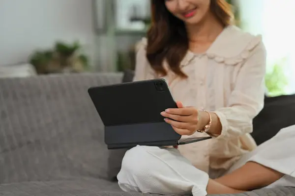 Smiling young woman in casual clothes browsing internet on digital tablet. People and technology concept.