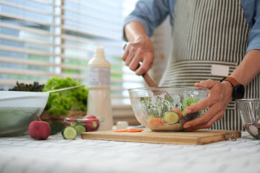 Son sınıf öğrencisi mutfakta taze vejetaryen salatası karıştırıyor. Sağlıklı yaşam tarzı kavramı