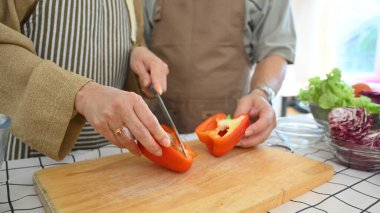 Son sınıf öğrencisi kadın mutfakta sağlıklı salata hazırlarken tahtada dolma biber kesiyor.