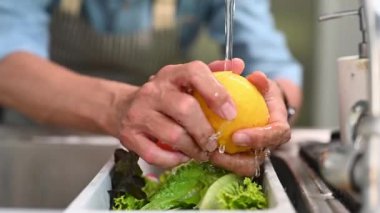 Mutfaktaki lavaboda limon yıkayarak taze salata hazırlayan son sınıf öğrencisinin resmini çek..
