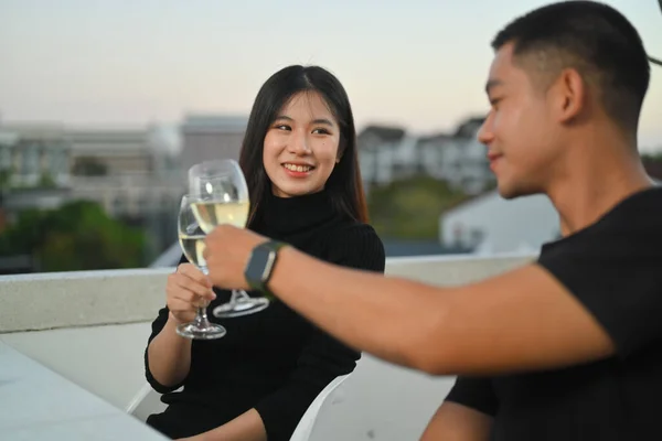 Young Asian couple toasting champagne and spending time at rooftop bar with alcohol drinks