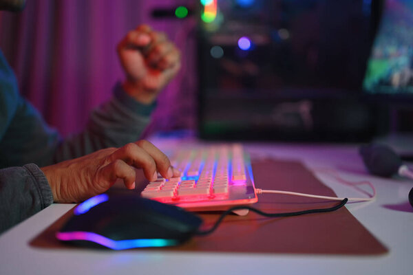 Крупный план мужчины-геймера, печатающего на игровой клавиатуре с RGB-светом. Концепция игр, развлечений и технологий