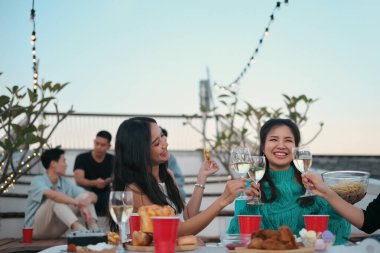 Mutlu gençler çatıdaki partide eğleniyor. İçkilerle şıngırdıyor..