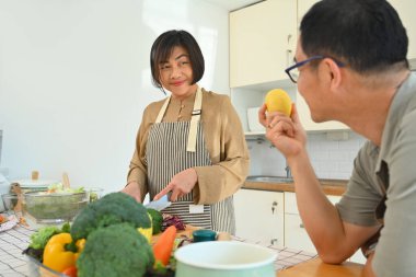 Mutlu orta yaşlı çift mutfakta vejetaryen salatası hazırlıyor..