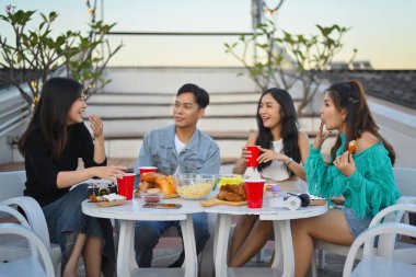 Bir grup genç arkadaş akşam çatıdaki partide eğleniyor ve içiyorlar..