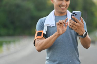 Açık hava eğitiminden sonra cep telefonu kullanan tatmin olmuş bir sporcu..