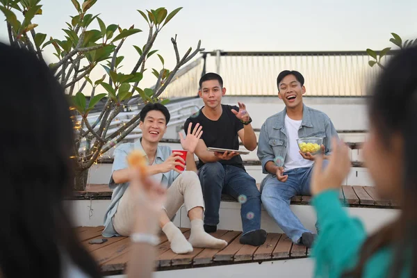 Happy young people gathered together having fun enjoy chill at outdoor rooftop party with drinks