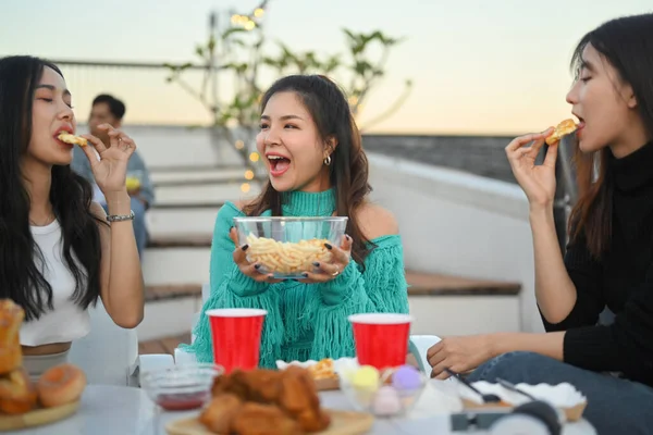 Group of Asian millennial friends enjoying dinner party at rooftop during sunset