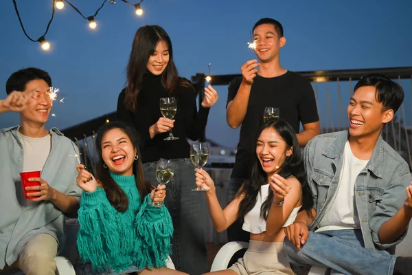 Group of young adult friends laughing and having fun at rooftop party. Friendship lifestyle concept.