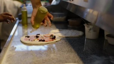  Masada pizza yapma süreci. Adam pişirmeden önce el yapımı pizzaya zeytinyağı döküyor..