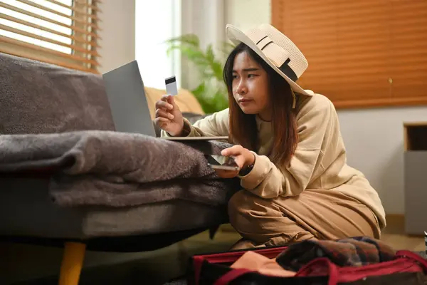 Young woman holding credit card and making hotel reservation on digital tablet.