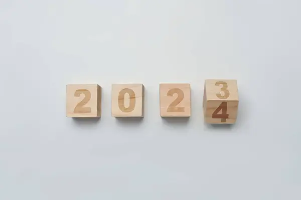 Wood cubes or blocks turning year from 2023 to 2024. Start new year, beginning and business target strategy concept.