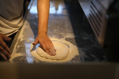 Şef mutfak masasında un ile pizza hamuru yoğuruyor. Fırın ya da pizza pişirme konsepti.