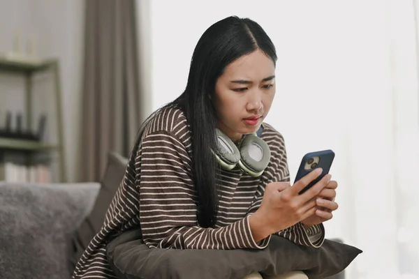 Serious young woman getting problems with mobile phone, chatting in social network.