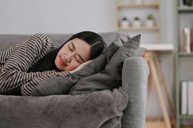 Genç bir kadın gündüzleri uyukluyor oturma odasında kanepede uyuyor..