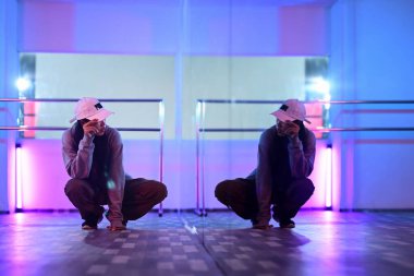 Çekici genç bir kadın profesyonel hip hop dansçısı aynanın önünde renkli neon ışıklı bir stüdyoda oturuyor..